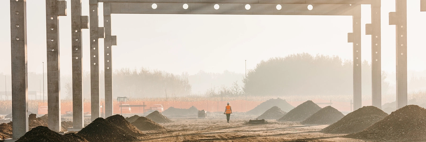 A man walks through a construction site with piles of construction materials.